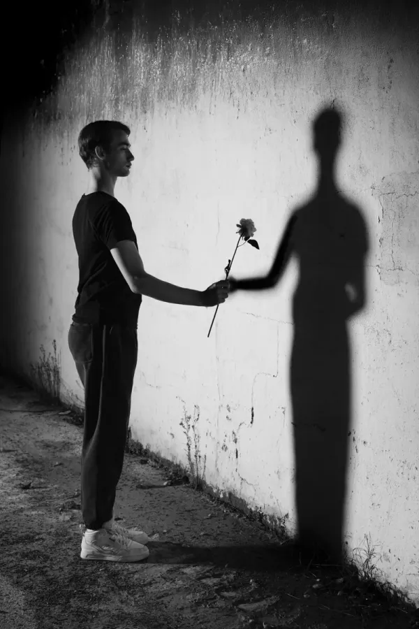 ARJAN SPANNENBURG, WORTHY, conceptual monochrome art of a man offering a rose to his shadow as a symbol of self-value.